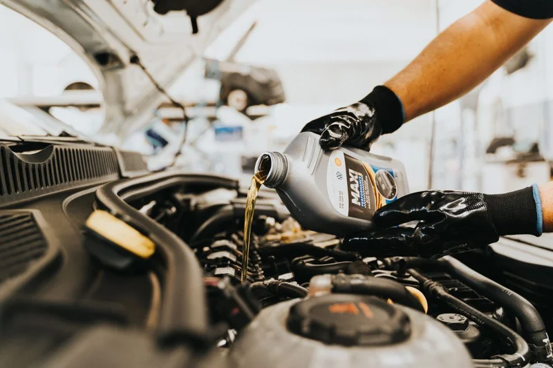 Mechanic pouring engine oil into a vehicle engine during maintenance
