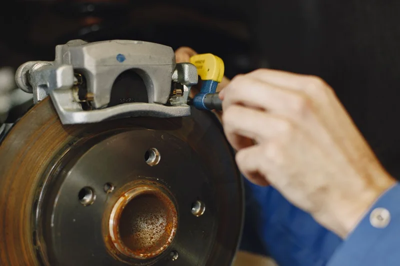 Technician inspecting brake caliper assembly on vehicle rotor